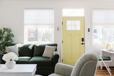 a living room with a green couch and a yellow door at Brass Apple Cottage in Campbell River