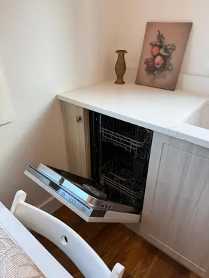 a fireplace in a counter with a painting and a chair at Brass Apple Cottage in Campbell River