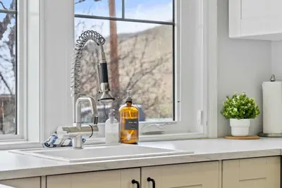 a kitchen sink with a bottle of alcohol next to a window at Local Loft - Downtown Okotoks - 2BD - Private in Okotoks