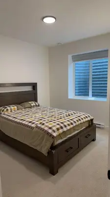 a bedroom with a bed in a room with a window at Basement suite -Langley Willoughby in Langley