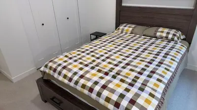 a bedroom with a bed with a checkered blanket at Basement suite -Langley Willoughby in Langley