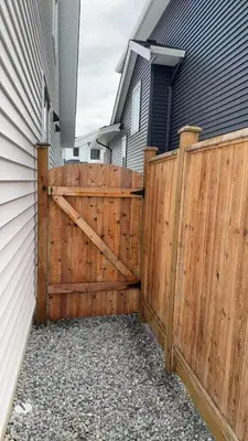 a wooden fence with a gate in front of a house at Basement suite -Langley Willoughby in Langley