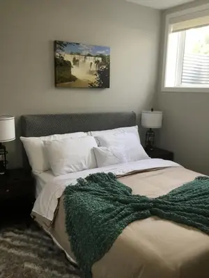 a bedroom with a bed with a green blanket on it at Almost Heaven - Cozy 2BDRM APT near Heritage Park,Spruce Meadows & Banff-SW Calgary in Calgary