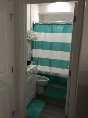 a bathroom with a green and white shower curtain at Almost Heaven - Cozy 2BDRM APT near Heritage Park,Spruce Meadows & Banff-SW Calgary in Calgary
