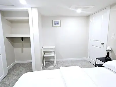 a white bedroom with two beds and a chair at A Cozy Home away from Home in Edmonton