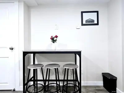 a black table with three stools and a vase with flowers at A Cozy Home away from Home in Edmonton