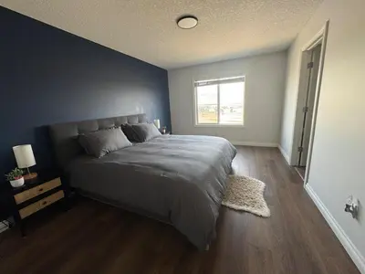a bedroom with a large bed with a blue wall at Exquisite Entire 4- Bed rooms vacation home! in Calgary