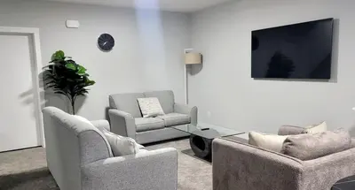 a living room with two chairs and a flat screen tv at Cozy 1 bedroom basement suite in Southwest Calgary in Calgary