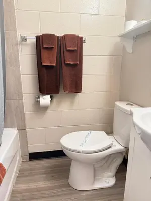 a bathroom with a toilet and a sink and towels at Athabasca Hillside Motel in Athabasca