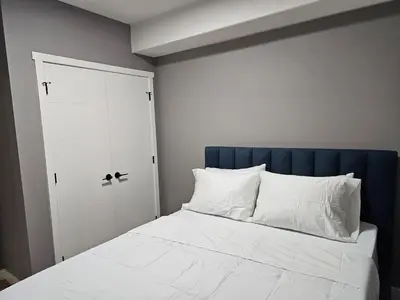 a bedroom with a white bed with a blue headboard at Lovely Brand New 2 Bedroom Suite in Calgary in Calgary