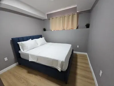a small bedroom with a bed with a blue headboard at Lovely Brand New 2 Bedroom Suite in Calgary in Calgary