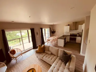 a living room with a couch and a kitchen at Haven On The Hill in Port Renfrew