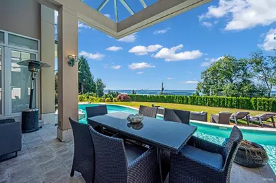 a patio with a table and chairs next to a swimming pool at Spectacular, Water View House! Property overview! in West Vancouver