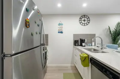 a kitchen with a stainless steel refrigerator and a sink at Tropical Caribbean-Themed Cozy Getaway - King Bed-Free Parking in Calgary