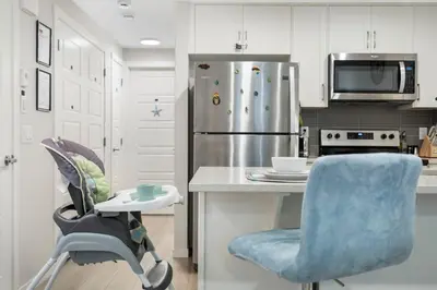a kitchen with a blue chair and a refrigerator at Tropical Caribbean-Themed Cozy Getaway - King Bed-Free Parking in Calgary