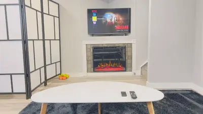 a living room with a fireplace with a tv above it at Calgary Airport Stay Private Suite 1Bed in Calgary