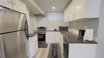 a kitchen with white cabinets and a stainless steel refrigerator at Calgary Airport Stay Private Suite 1Bed in Calgary