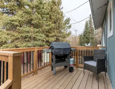 a barbecue grill on a deck with a chair at Modern Downtown Stay in Yellowknife