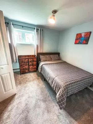 a bedroom with a bed and a dresser and a window at Modern Downtown Stay in Yellowknife