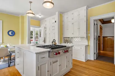 a kitchen with white cabinets and a stove top oven at Historic Treend Residence in the heart of Mission Calgary in Calgary