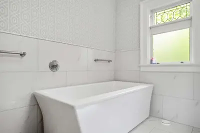a white bathroom with a tub and a window at Historic Treend Residence in the heart of Mission Calgary in Calgary