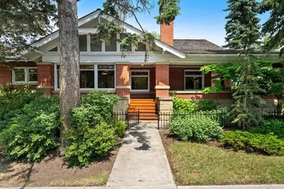 a red brick house with a porch and a tree at Historic Treend Residence in the heart of Mission Calgary in Calgary