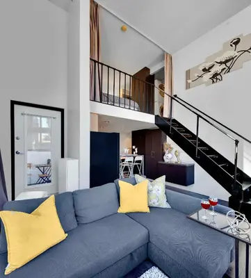 a living room with a blue couch with yellow pillows at Trendy Downtown Loft Apartment - King Bed! in Vancouver