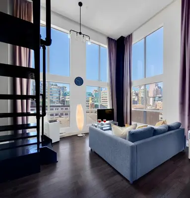 a living room with a couch and large windows at Trendy Downtown Loft Apartment - King Bed! in Vancouver