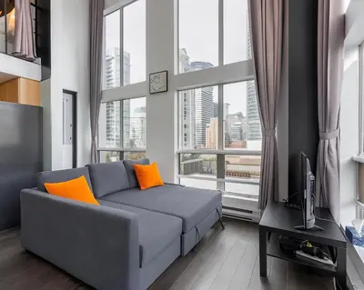 a living room with a couch and a large window at Trendy Downtown Loft Apartment - King Bed! in Vancouver
