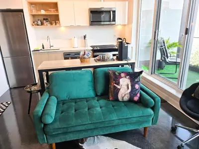a green couch in a living room with a kitchen at Boutique Studio City Views, Patio, Fireplace Voglio Bene in Calgary