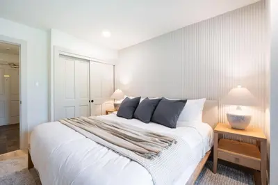 a bedroom with a large white bed with two lamps at Greystone Lodge by Outpost Whistler in Whistler
