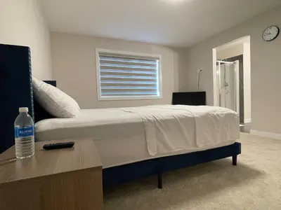 a bedroom with a bed and a bottle of water on a table at Full AC Brand New House with 3 Bedroom in Airdrie