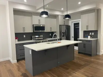 a kitchen with white and gray cabinets and a sink at Full AC Brand New House with 3 Bedroom in Airdrie