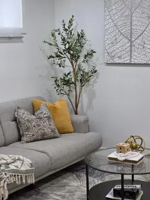 a living room with a gray couch and a tree at Amaville- The Cozy Cave - Minutes to WEM & YEG in Edmonton