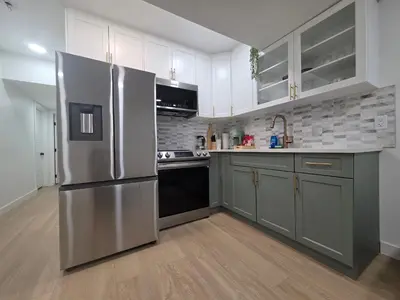 a kitchen with a stainless steel refrigerator and white cabinets at Amaville- The Cozy Cave - Minutes to WEM & YEG in Edmonton
