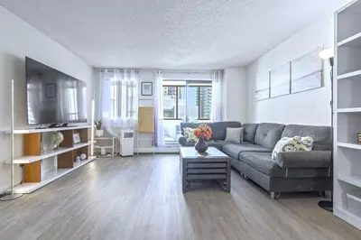 a living room with a couch and a table at Cozy & Spacious 2BR at Stampede w Parking and AC in Calgary