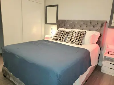 a bedroom with a large bed with a blue blanket at Winter Deal! Stunning Ocean View Modern 1 BDR Private Entry Suite in Colwood