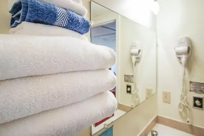 a stack of towels in a bathroom with a mirror at Gables Motel in Radium Hot Springs