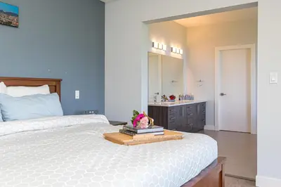 a bedroom with a bed with a sink and a mirror at Come On In, The Water View Is Waiting For You,,, in Oak Bay