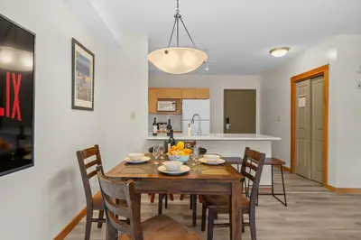 a kitchen and dining room with a wooden table and chairs at Heated Outdoor Pool & Tubs 9 Guests in Canmore