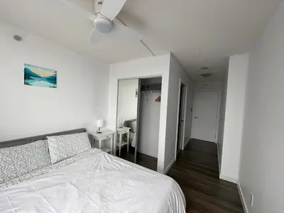 a white bedroom with a bed and a hallway at Lucy's House in Vancouver