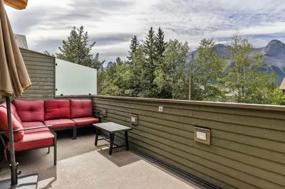 a balcony with red chairs and a view of the mountains at Alps #201- LEED Gold Certified in Canmore