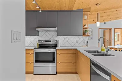 a kitchen with stainless steel appliances and wooden cabinets at Pyrenees #202 - LEED Gold Certified in Canmore
