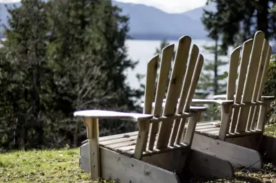 two wooden chairs sitting in the grass near the water at Quarrystone House B&B in Fernwood