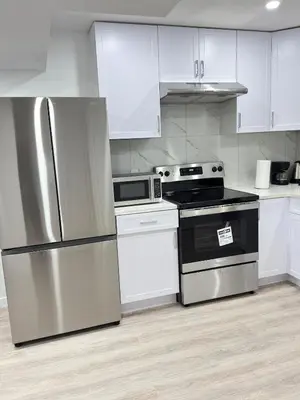 a kitchen with stainless steel appliances and white cabinets at Modern Comfort in West Edmonton in Edmonton