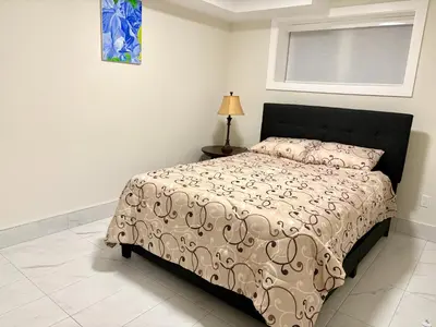 a bedroom with a bed and a lamp and a window at Sunny White Rock 2BR, Steps to Sand, Brand New Stay in White Rock