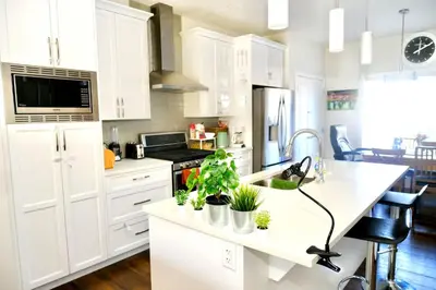 a kitchen with white cabinets and plants on a counter at Mahogany Loft Retreat - 3 Story Home in Calgary