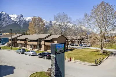 a sign in front of a building with mountains in the background at Comfy Rockies Retreat for 4 Canmore DT Near Banff in Canmore