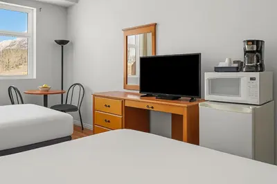 a bedroom with a bed and a television on a desk at Comfy Rockies Retreat for 4 Canmore DT Near Banff in Canmore