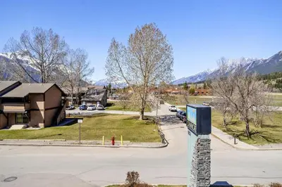 a street sign in front of a house with mountains at Cozy Hideaway with MTN Views Near DT Canmore and Banff in Canmore